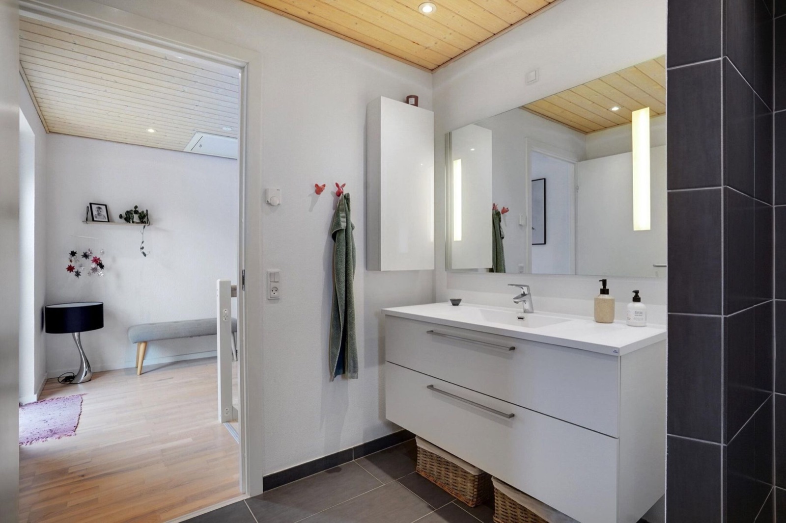 Ljust nordiskt badrum med vitt handfat, kromad blandare och spegel.